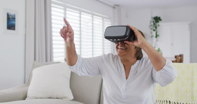Happy african american senior woman sitting on couch enjoying using vr headset