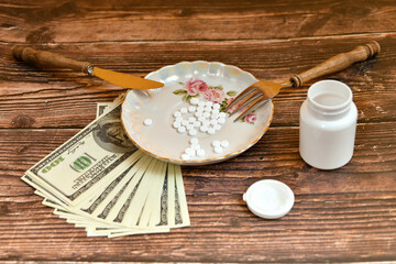 A plate of various medicinal pills is on dollar bills. The knife and fork are on the plate.
