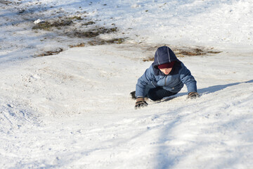 Fototapeta na wymiar A boy climbs a snow slide for downhill and sledding and skiing.