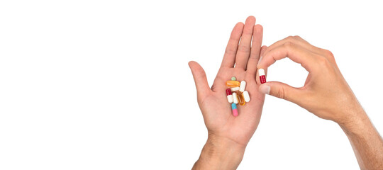 A man's hand is full of a large pile of different pills on white background. Treatment concept. Copy space © Atlas