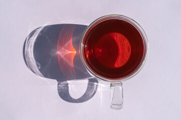 a mug of tea with a hard shadow on an purple background