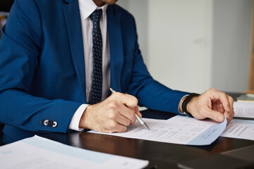 Cropped portrait of successful businessman signing contract at desk in office, copy space