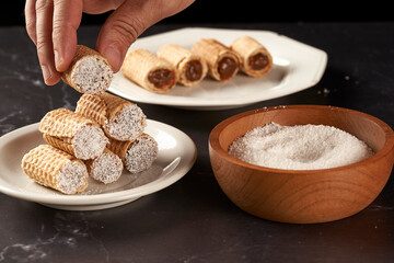 hand holding cubanitos with dulce de leche and grated coconut. cuchufli.