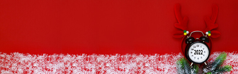 Merry Christmas 2022. The numbers 2022 on the clock. red background and white snow. New year...