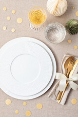Fototapeta na wymiar Festive christmas table setting with golden cutlery and porcelain plate and christmas decoration. Mockup for place card, dinner invitation, restaurant menu template. Copy space
