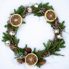 Handmade wreath with spruce twigs in the snow. Winter decor.