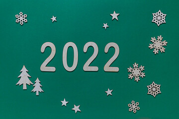 New Year's composition on a green background with wooden numbers 2022, snowflakes, sweet caramel, Christmas toy Christmas tree. Flat lay, top view, christmas card