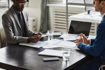 Cropped shot of of two businessmen discussing contract at table during meeting in office, copy space