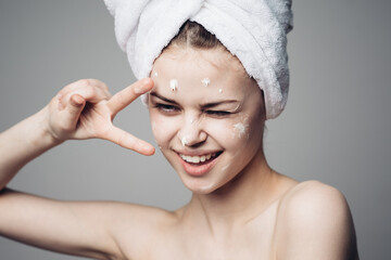 woman with bare shoulders towel on head face cream skin care