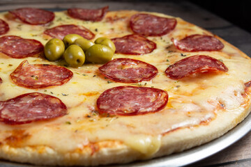 pizza recien horneada con rodajas de salame y queso caliente