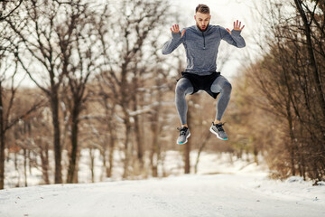 Sportsman jumping high in nature at snowy winter day. Healthy habits, winter sport