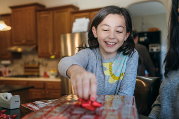 Girl wrapping Christmas present in home kitchen