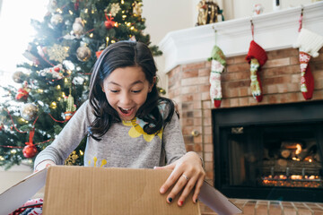 Girl excited about present in front of Christmas tree