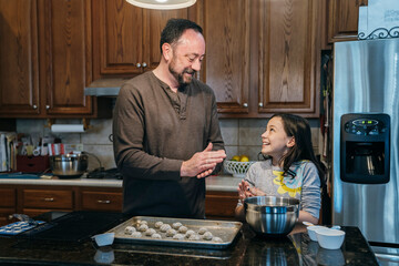 Dad teaching daughter to make Christmas cookies in home kitchen