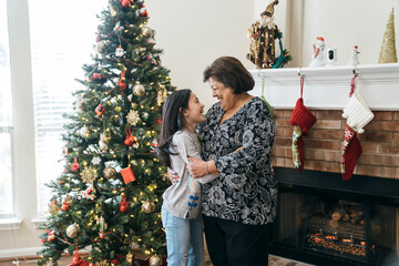 Girl hugging grandma in front of Christmas tree