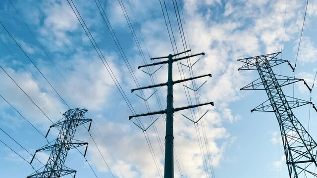 Overhead power electricity transmission towers below a blue sky.