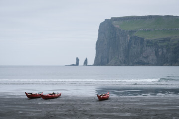 Kayaks by the ocean in the village of Tjornuvik, Faroe Islands