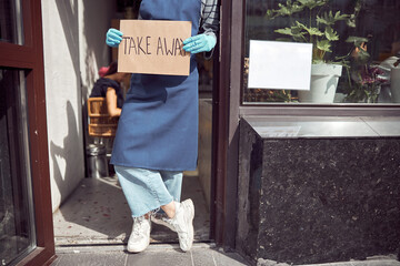 Fototapeta na wymiar Asian employer holding take away sign before cafe entrance