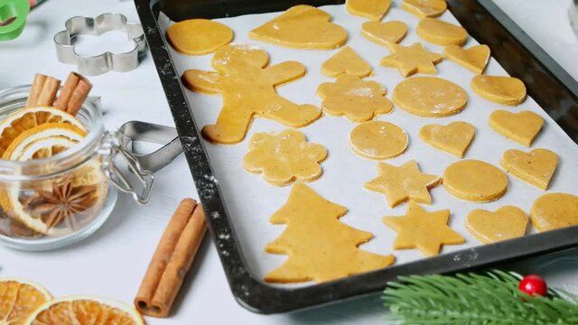 Gingerbread cookies on baking sheet, metal cutter, Christmas spices and decoration, dolly shot