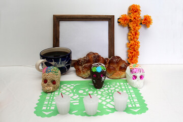 Sweet in the shape of a skull made of sugar, chocolate and amaranth as an offering for the Day of the faithful departed and all the saints together with cempasuhil, candles and photo frame

