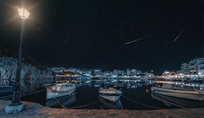 Pioggia di Perseidi nel cielo stellato sul lago Voulismeni di Agios Nikolaos a Creta