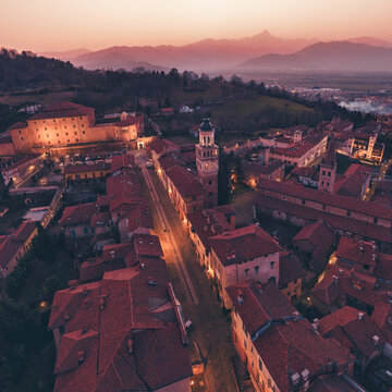 Veduta aerea del centro storico di Saluzzo dopo il tramonto, con il Monviso sullo sfondo