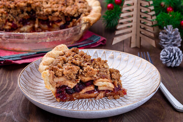 Slice of freshly baked American apple cranberry pie, topped with crumbled dough and pecan