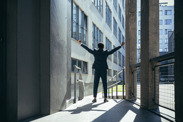 Successful african american businessman with arms up celebrating victory. Concept: success, career growth, victory, freedom. silhouette business man on the background a modern office building. outside