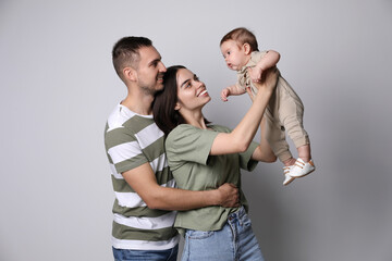 Happy family. Couple with their cute baby on grey background