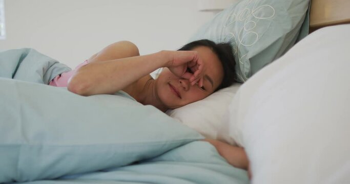Asian woman lying in bed, waking up in the morning