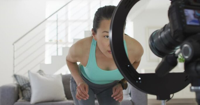 Happy asian woman preparing camera for making fitness vlog from home