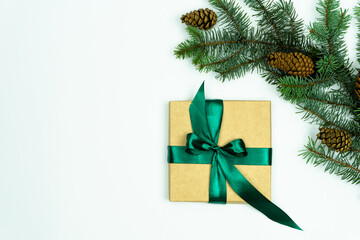 Christmas fir branch and cones. Gift box next to a fir branch on a white background. Christmas composition. Flat lay, top view, copy space