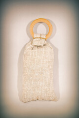 Small interior scent bag made of gray canvas with wood ring for home fragrance