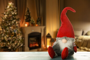 Funny Christmas gnome on turquoise wooden table in room with festive decorations. Space for text