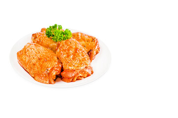 Raw marinated in red sauce chicken thighs on a white plate, on a white isolated background. Top of view.Isolated object, copy space.Raw chicken marinated. Chicken semi-cooked thighs.