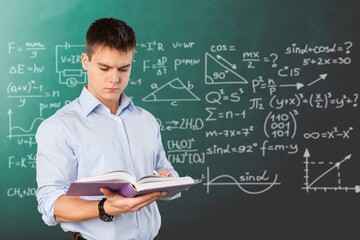 Young teacher man teaching holding book training the mathematics in classroom blackboard