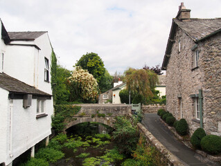 Fototapeta na wymiar view of the bridge crossing the river with surrounding village houses in cartmel, cumbria