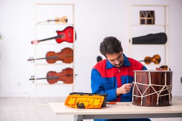 Young male repairman repairing musical instruments at workplace