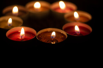 Candles are collected in a circle. A circle of wax candles. Liquid wax orange and red. Romantic atmosphere with open fire in the dark.