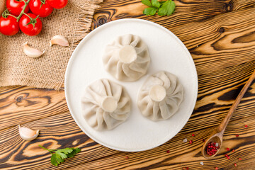 Khinkali with lamb on white plate, georgian cuisine on wooden table top view