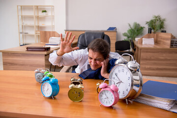 Young male employee sleeping in the office in time management co
