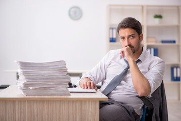 Naklejka premium Young male employee and too much work in the office