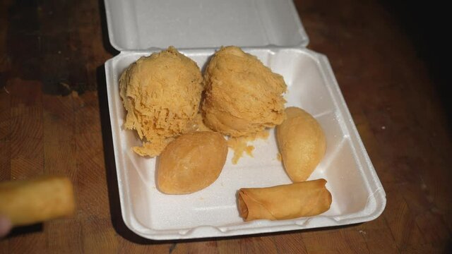This video shows a hands taking a fried egg roll from a dim sum box filled with delicious items like hom siu gok pastries.