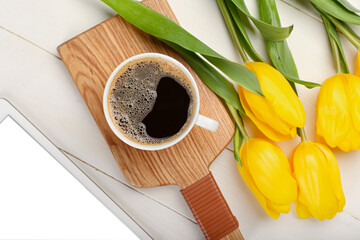 Cup of coffee and tulips on light wooden background