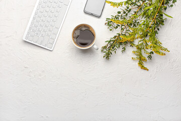 Cup of coffee, green branch and keyboard on light background