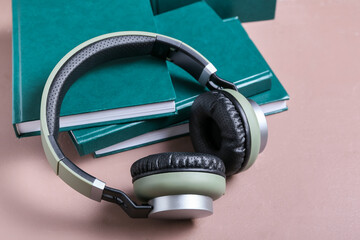 Modern headphones and books on color background