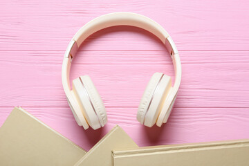 Modern headphones and book on color wooden background