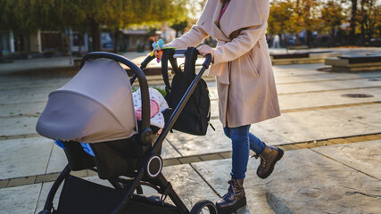 Close up on midsection of unknown caucasian woman mother pushing stroller with baby in the city in...