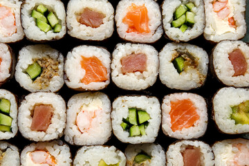 Many delicious sushi rolls as background