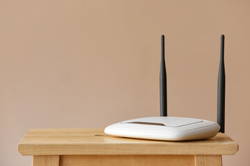 Modern wi-fi router on table near beige wall